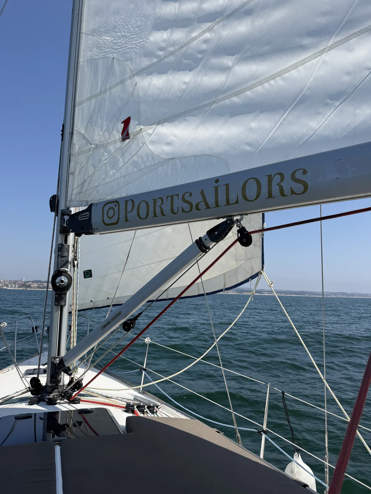 Blick nach vorn über den Bug eines Port-Sailors-Segelboots unter Segeln, die Küste von Porto am Horizont