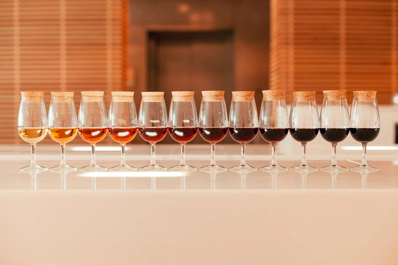 A row of tasting glasses showing Port wine graduating from pale white to deep ruby and tawny