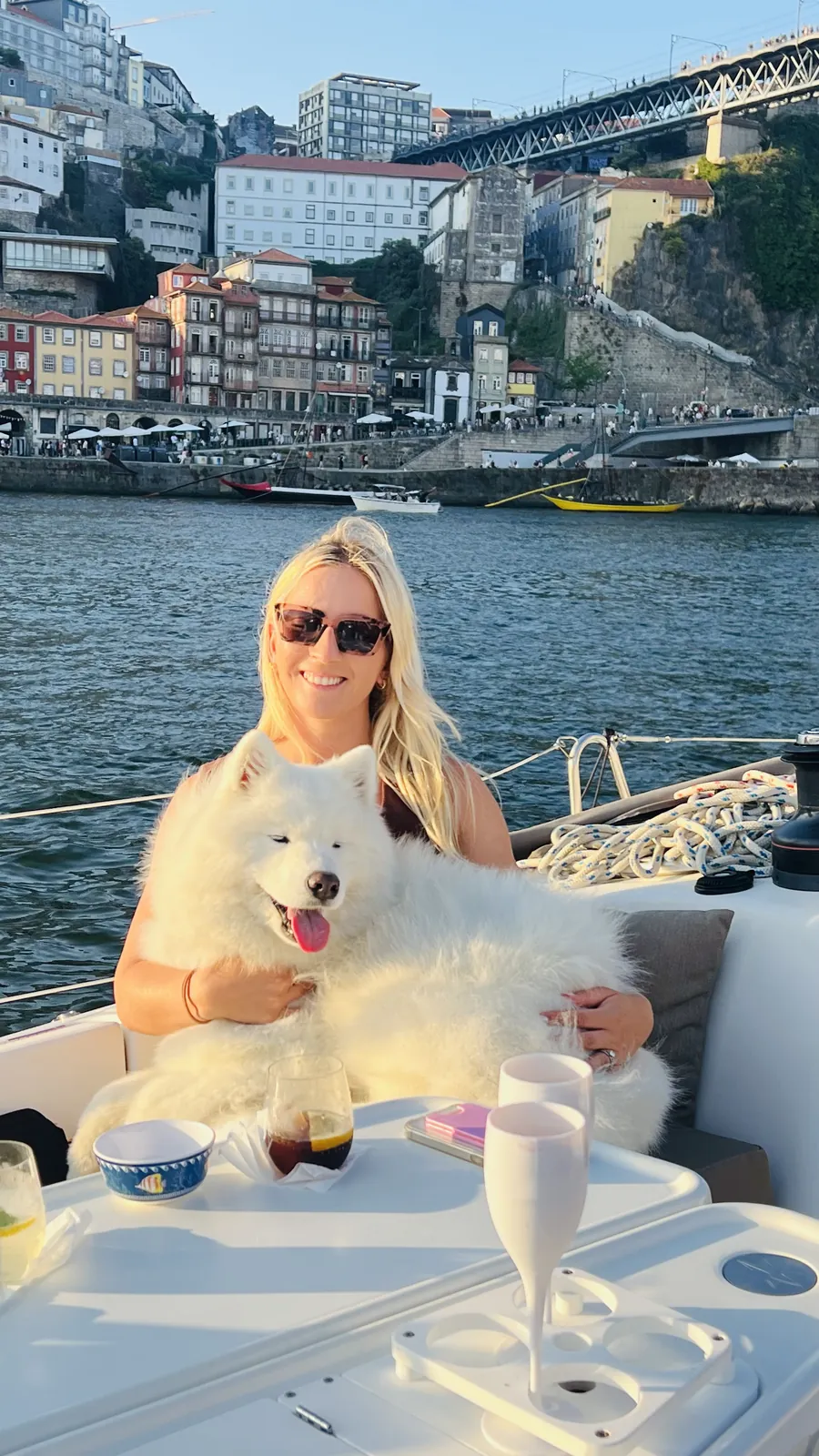 Cliente e um cão Samoiedo branco num veleiro dog-friendly em frente à Ribeira do Porto e ao Douro
