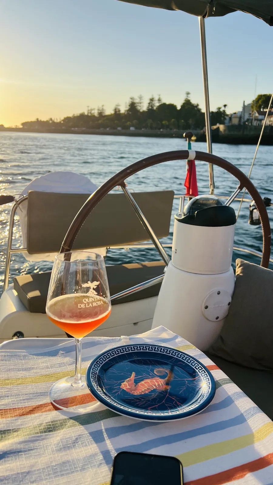 Vinho rosé e petisco de marisco servidos no convés junto à bandeira portuguesa ao pôr do sol