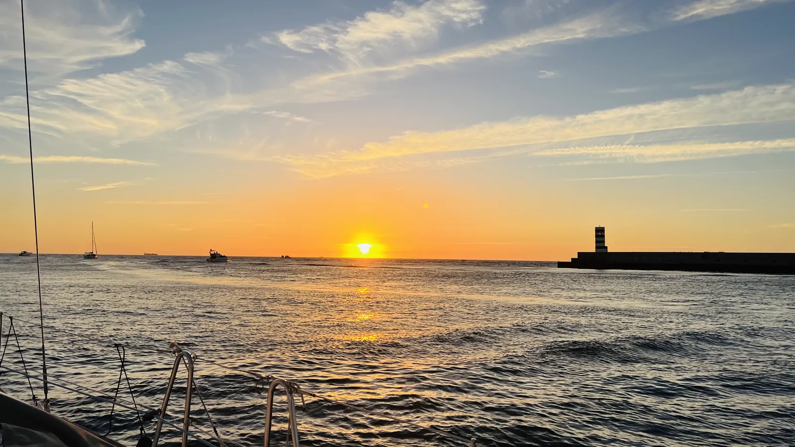 Amplo pôr do sol atlântico com um farol visto de um cruzeiro à vela no Porto