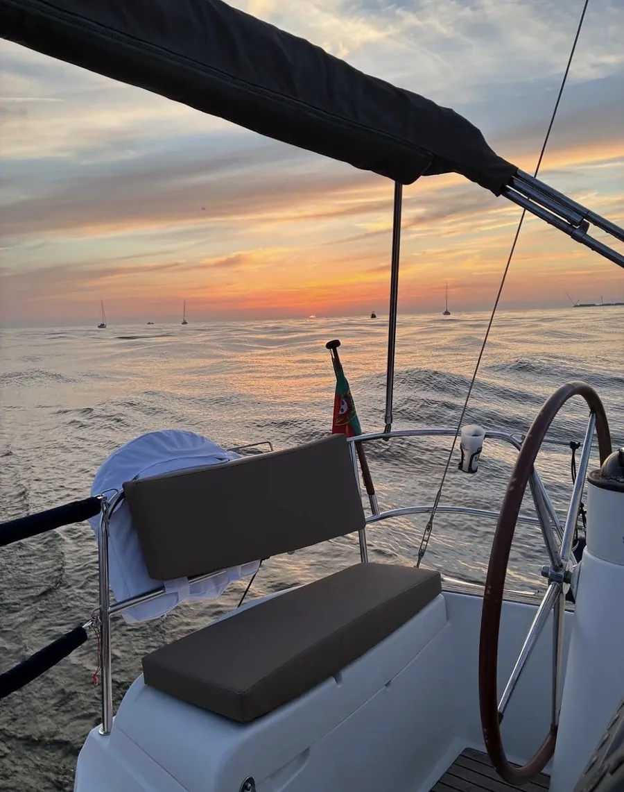 Leme e cockpit do veleiro banhados pela luz dourada do pôr do sol num cruzeiro no Porto