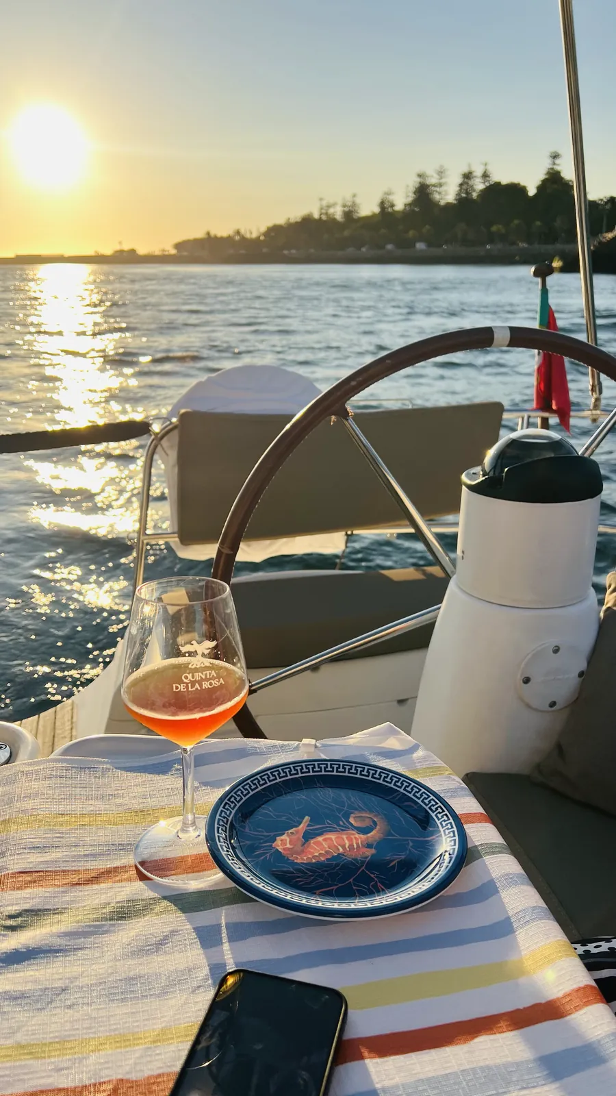 Copo de rosé e petiscos no convés enquanto o sol se põe sobre a Foz do Douro