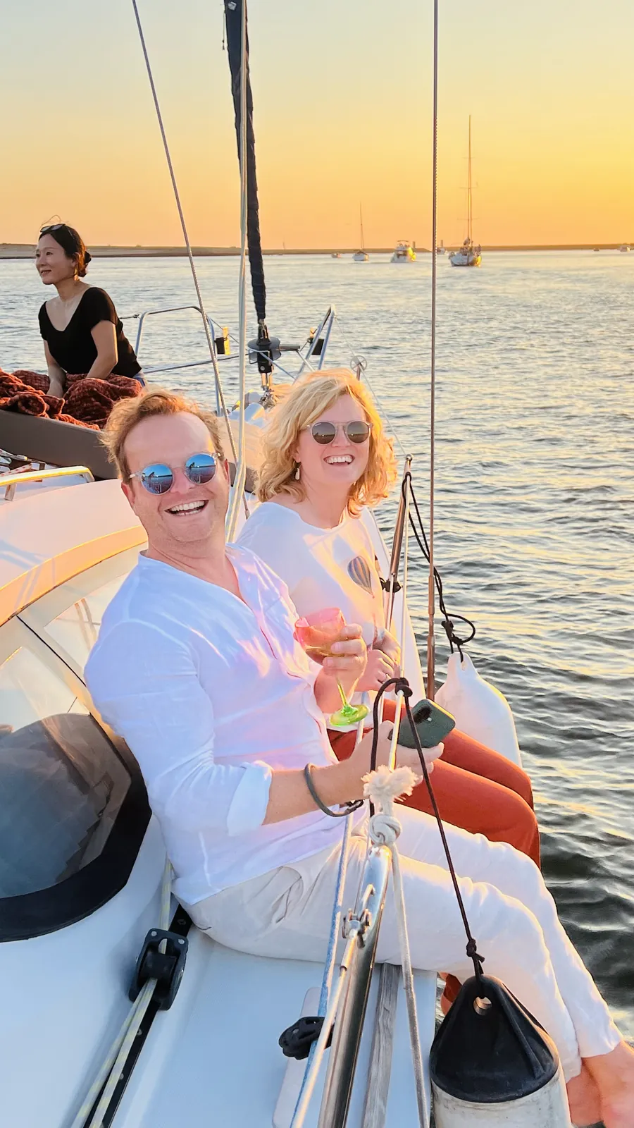 Duas amigas a celebrar com bebidas no convés durante uma navegação ao pôr do sol no Porto