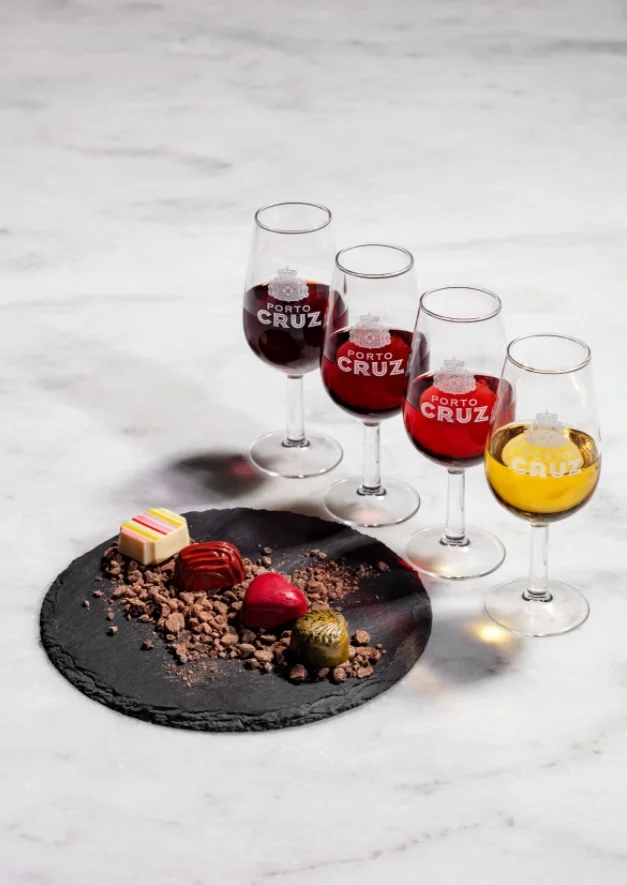 Four glasses of Port, red, tawny, rosé and white, beside artisan chocolate pralines on a slate plate